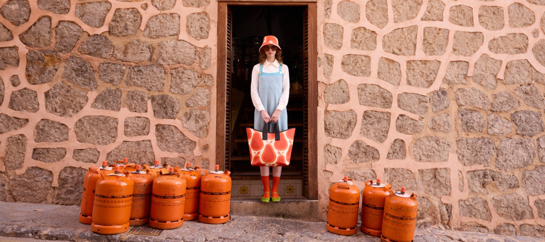 A women stands in a doorway, carrying a large tote bag with a red pear pattern