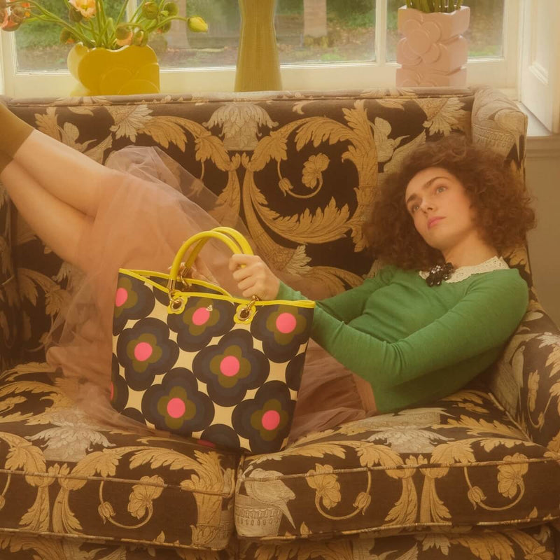 Model reclining on chair with Orla Kiely tote bag 