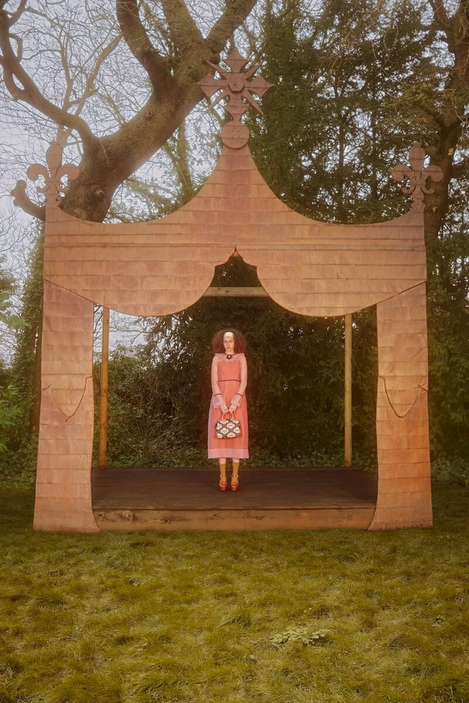 Model on stage in forest with Orla Kiely handbag 