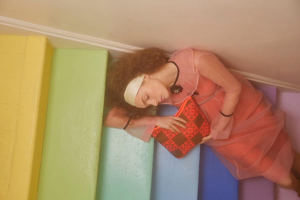 Model sleeping on stairs with an Orla Kiely Carrygrab bag 