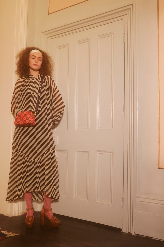 Model standing by doorway with tomato Orla Kiely babaluna bag