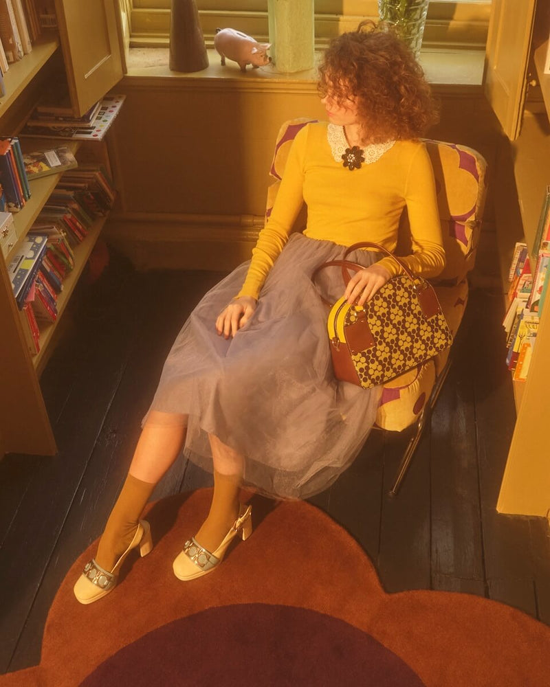 Model sitting on chair with Orla Kiely bowling bag 