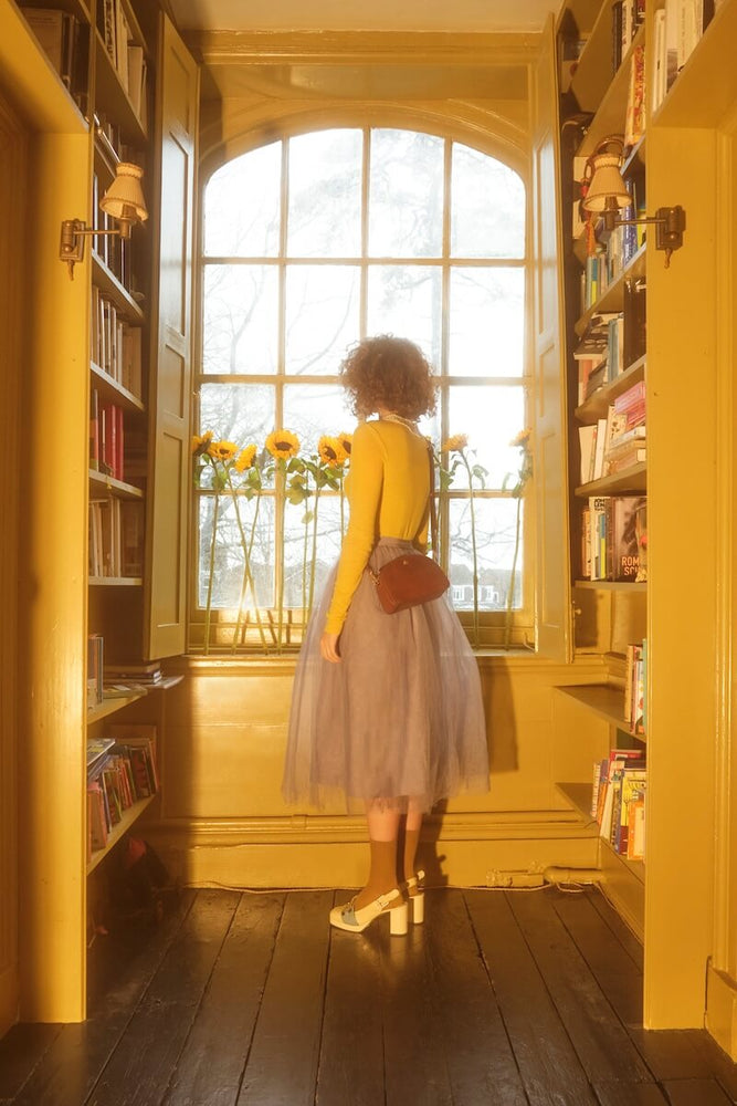 Model standing in library with leather Orla Kiely bag 