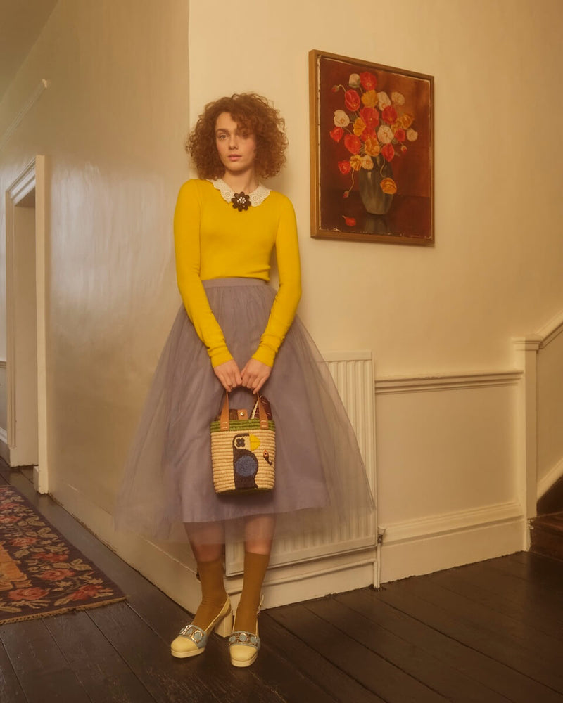 Model standing in a house with Orla Kiely sunday mini basket bag