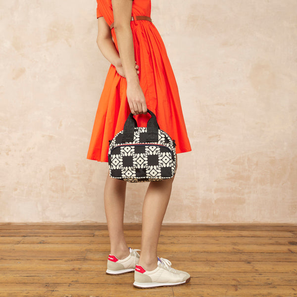 Model wearing the Radial Handbag in Lattice Flower Tile Onyx pattern by Orla Kiely