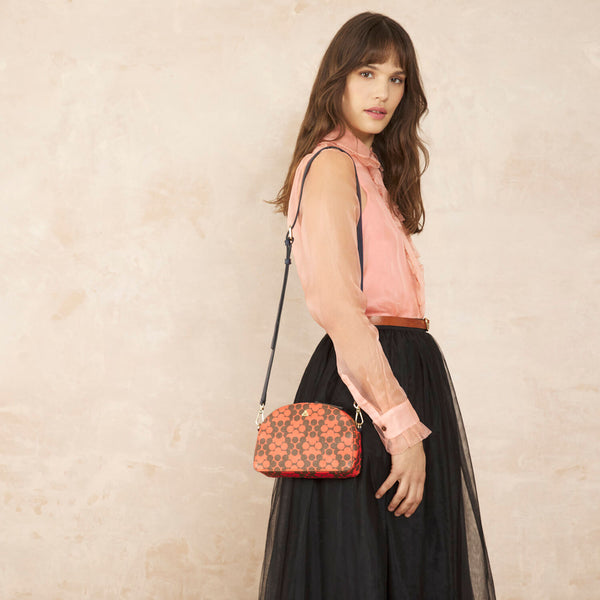 Model wearing the Babaluna Crossbody Handbag in Tomato Puzzle Flower pattern by Orla Kiely