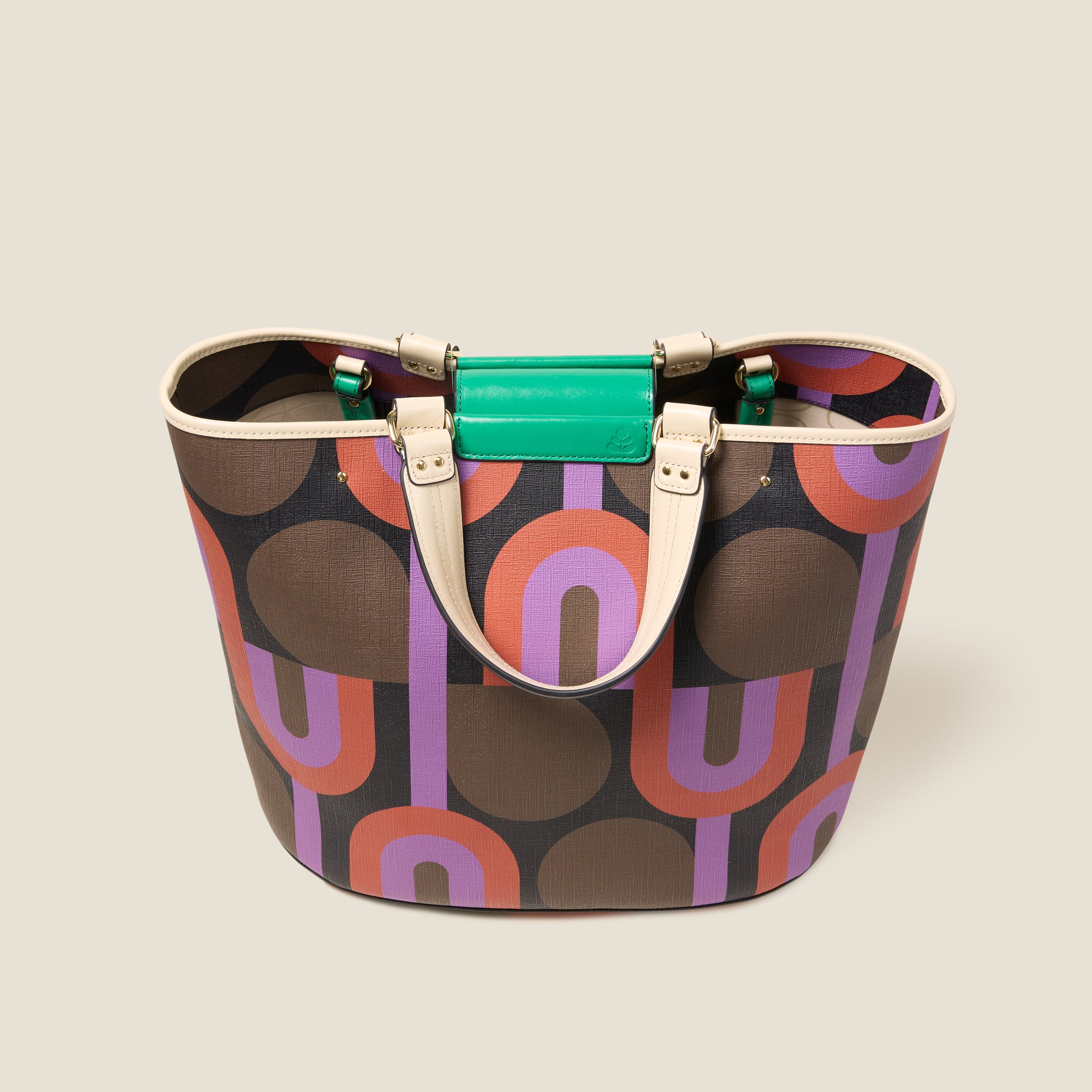Top view of a large tote bag with purple, red, brown and black retro inspired pattern, featuring leather grab handles and green branding.