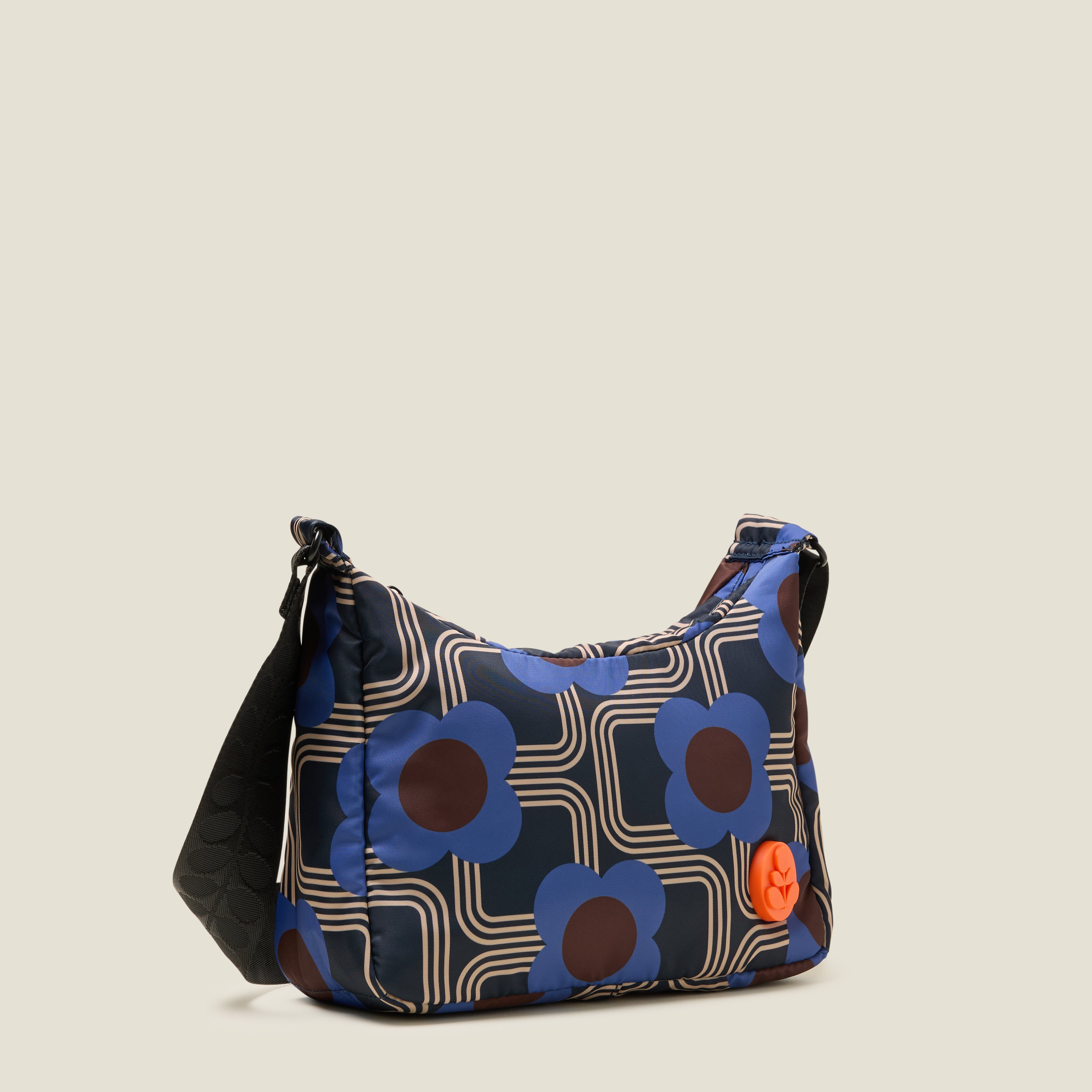 The side view of small hobo bag with blue floral pattern, orange stem logo branding and black adjustable strap.