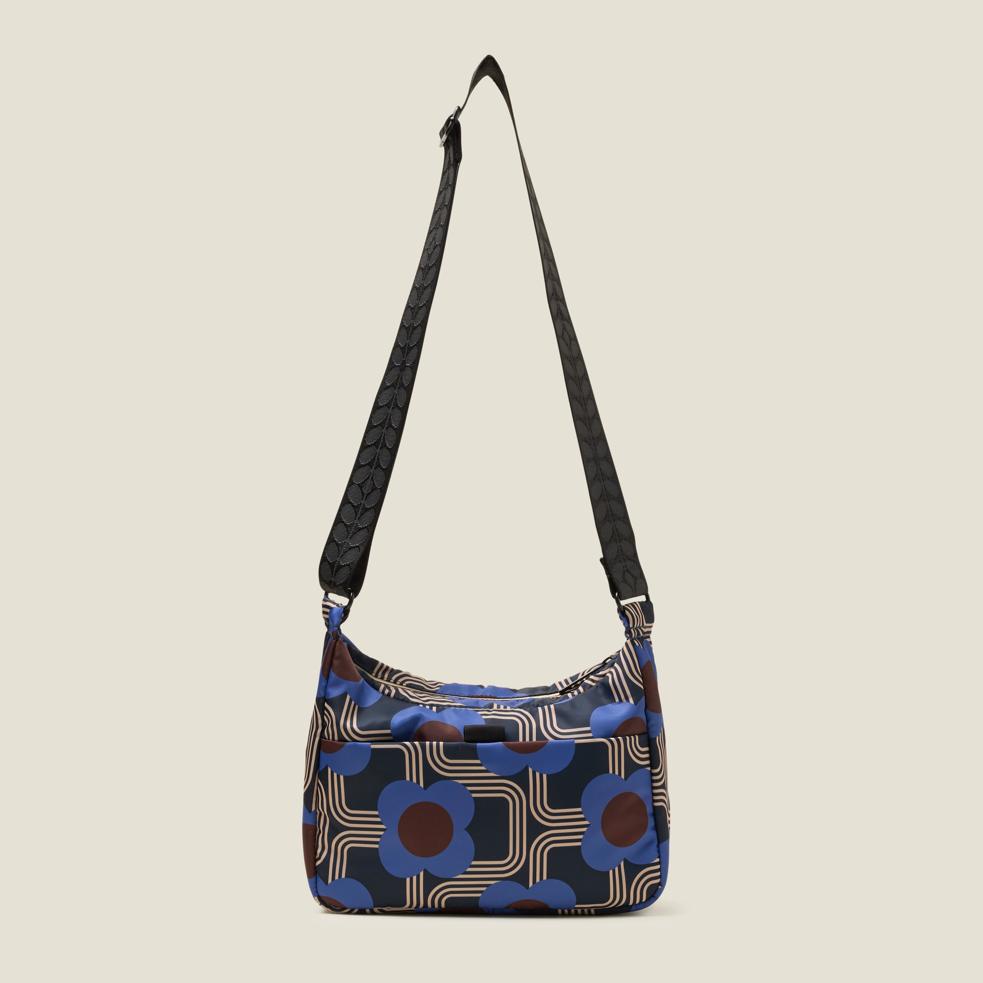 The back view of small hobo bag with cobalt blue floral pattern, back pocket and black adjustable strap.