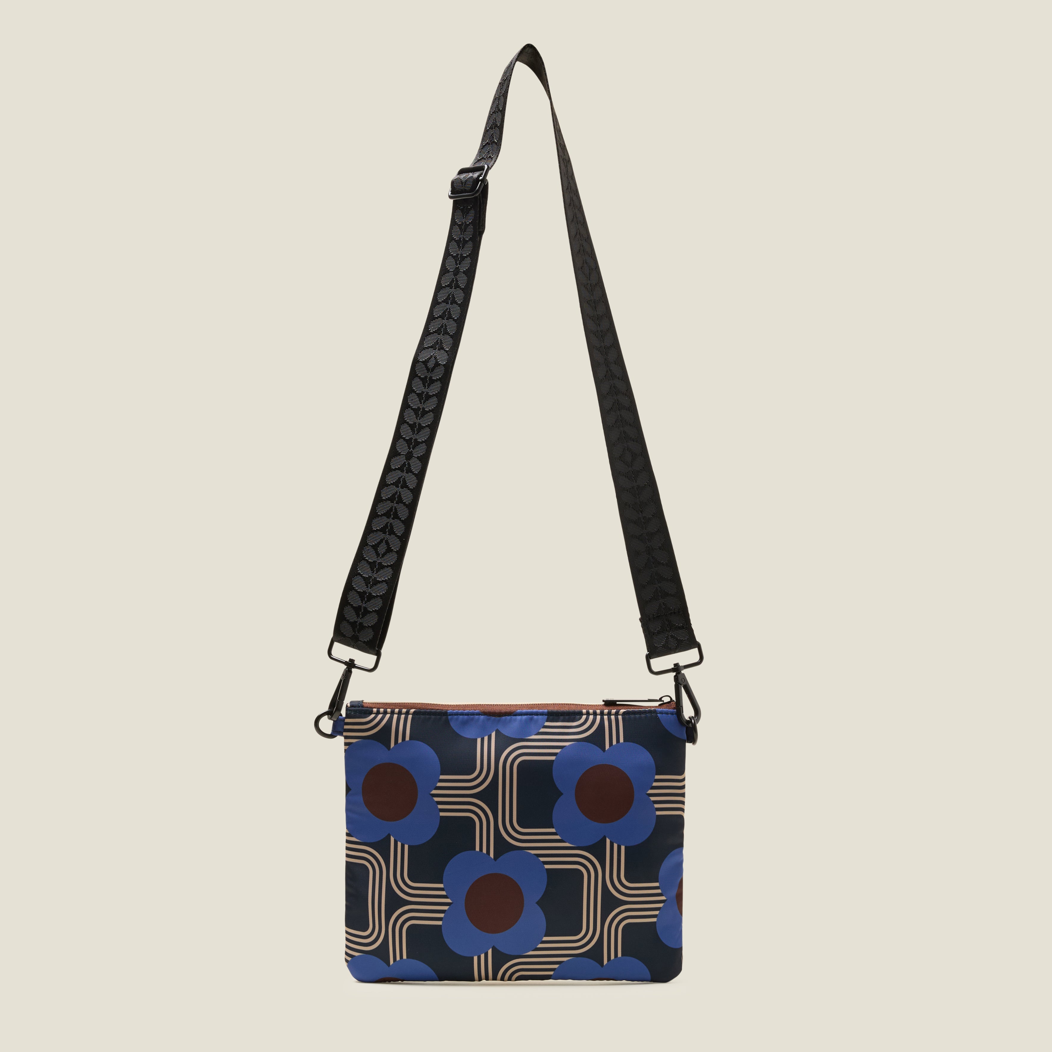 Crossbody bag with retro floral pattern in navy and cobalt blue, showing the crossbody strap at full length on a beige background