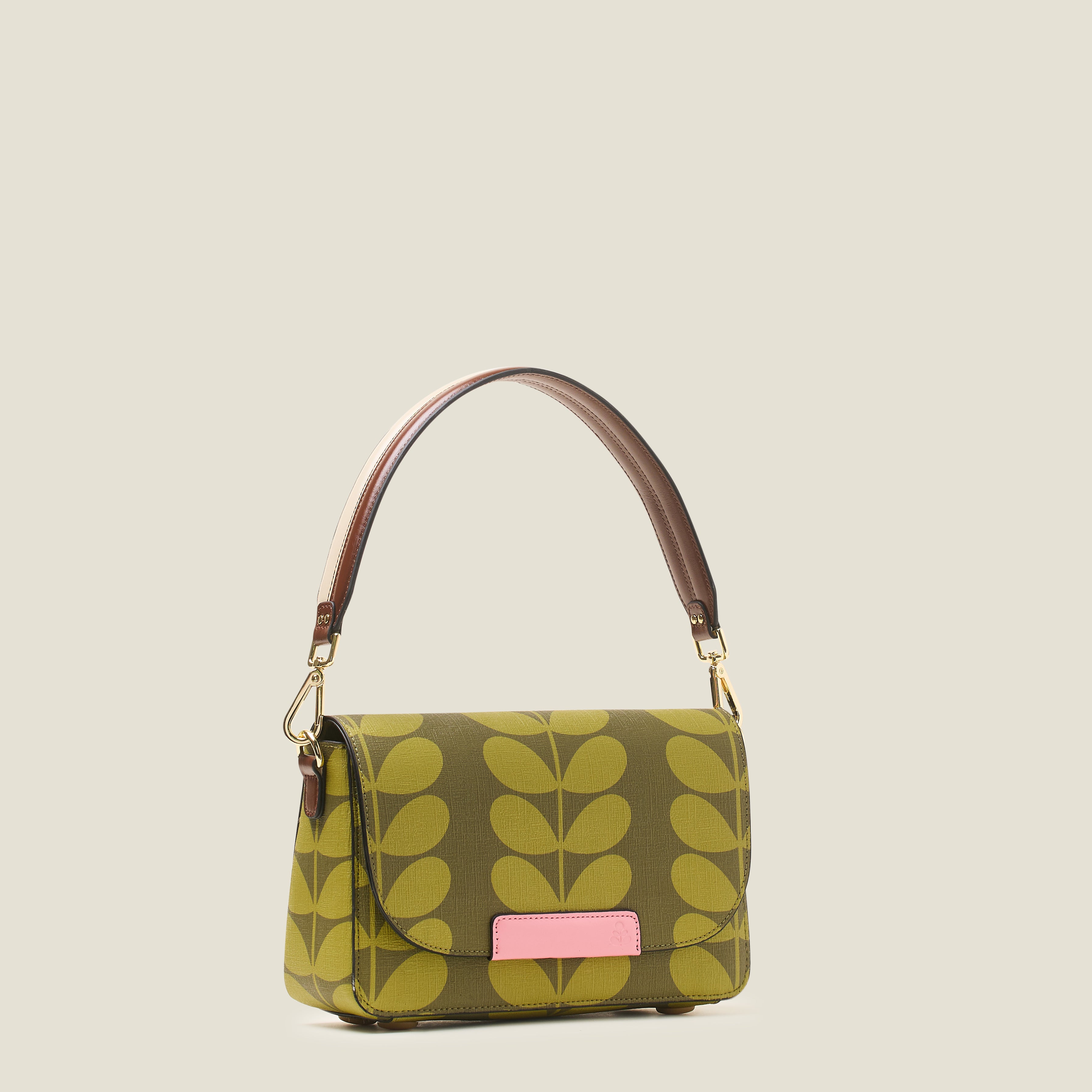 Side view of a women's handbag with green leaf pattern, featuring shoulder strap and pink branding.