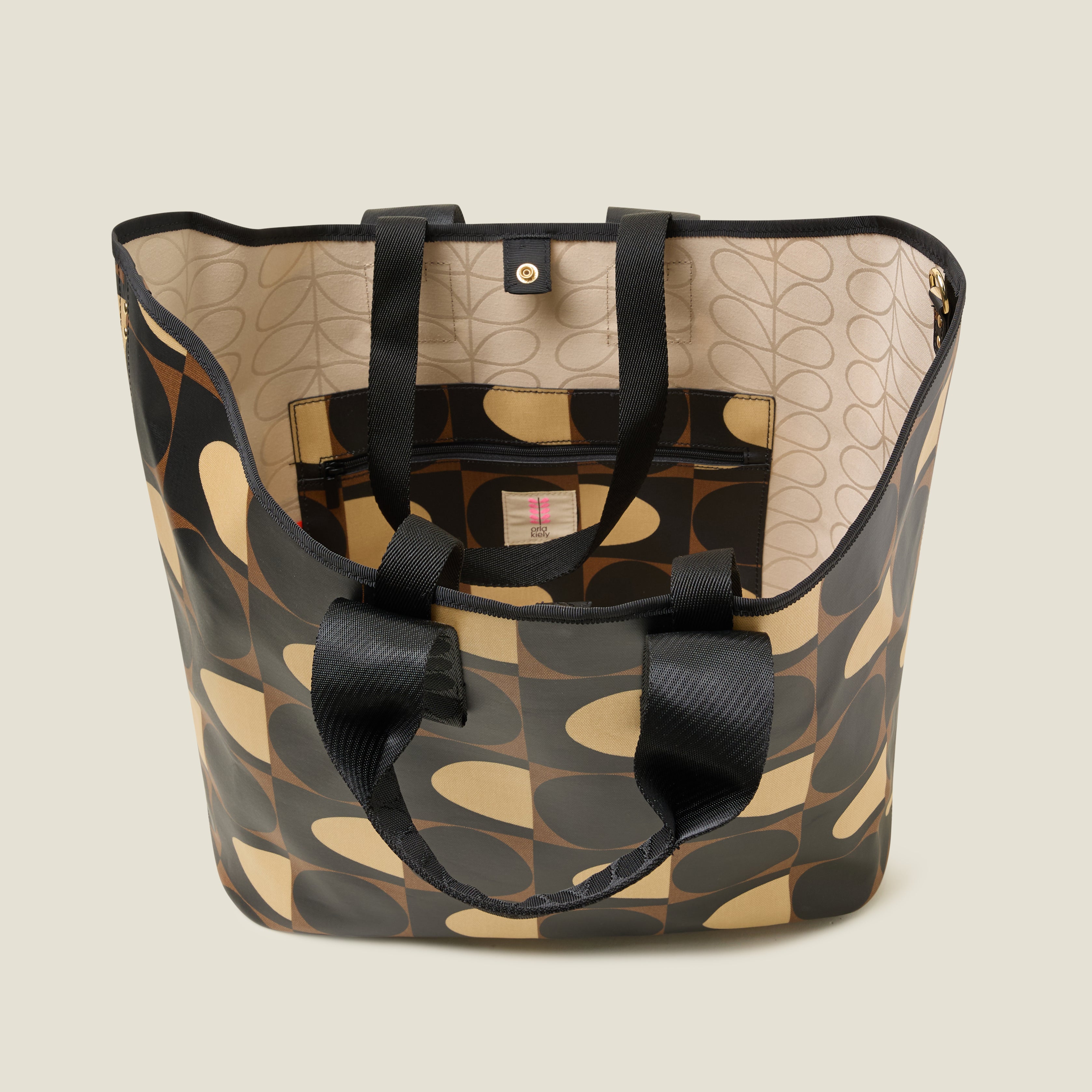 Top view of patterned tote bag with black, brown and beige spot square printed design, inside features a zip pocket and snapper fastening.