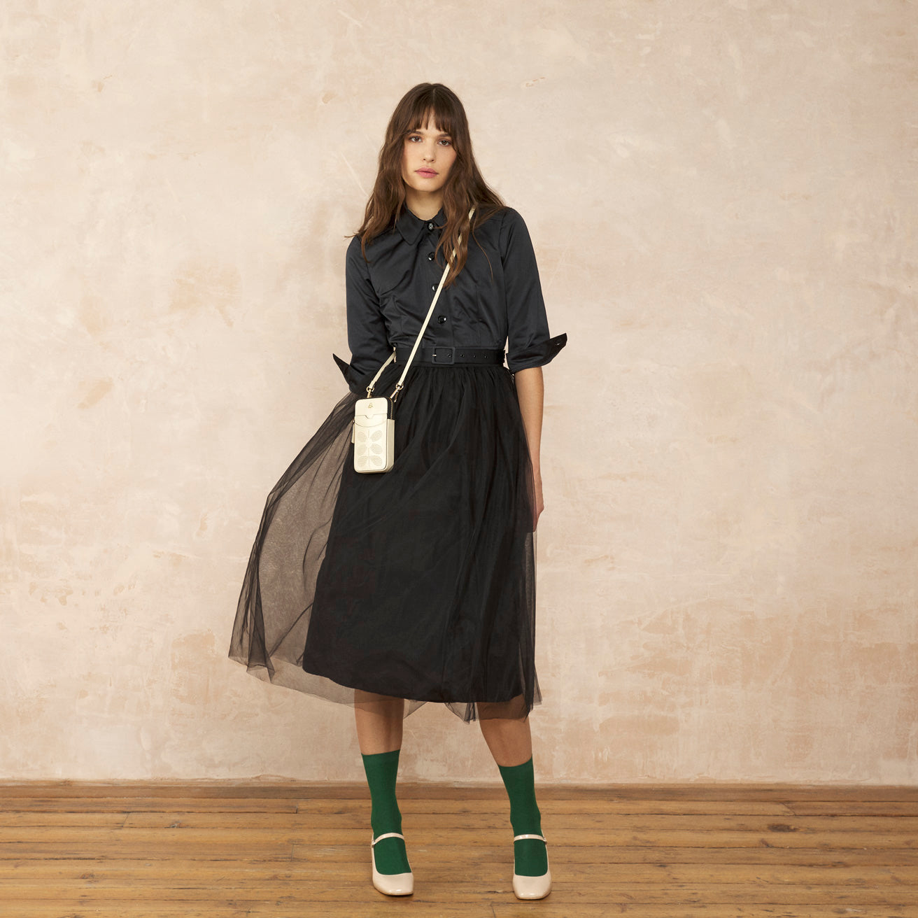 A model dressed in black with a white Orla Kiely ariel phone pouch