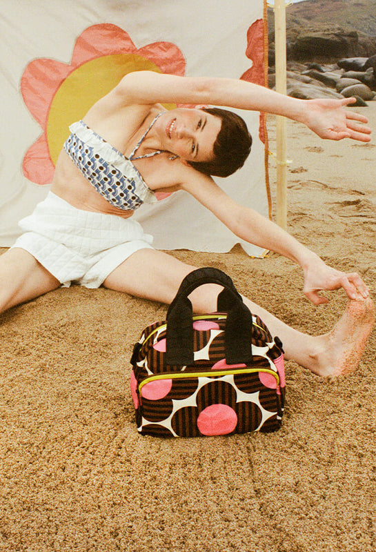 Model stretching on the beach with an Orla Kiely bag for good