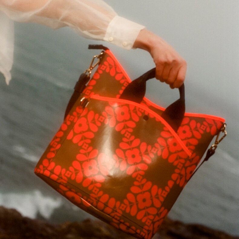 Model holding Orla Kiely carry grab bucket bag by the sea