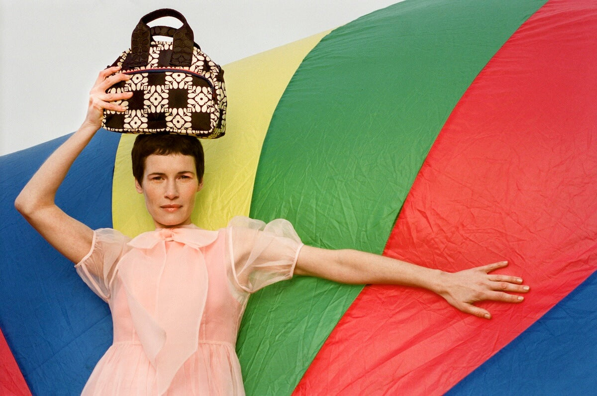 Model with outstretched arm and Orla Kiely radial bag on her head