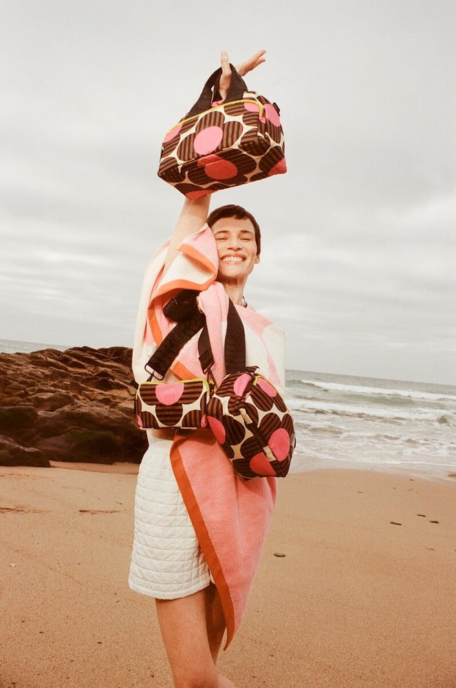 Model wrapped in blanket on the beach with Orla Kiely bags 