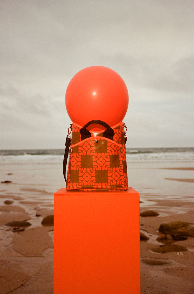 An orange ball on an orange Orla Kiely bag