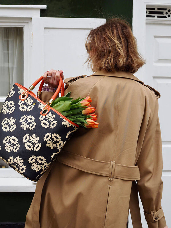 An influencer holding an Orla Kiely tote over her shoulder with tulips
