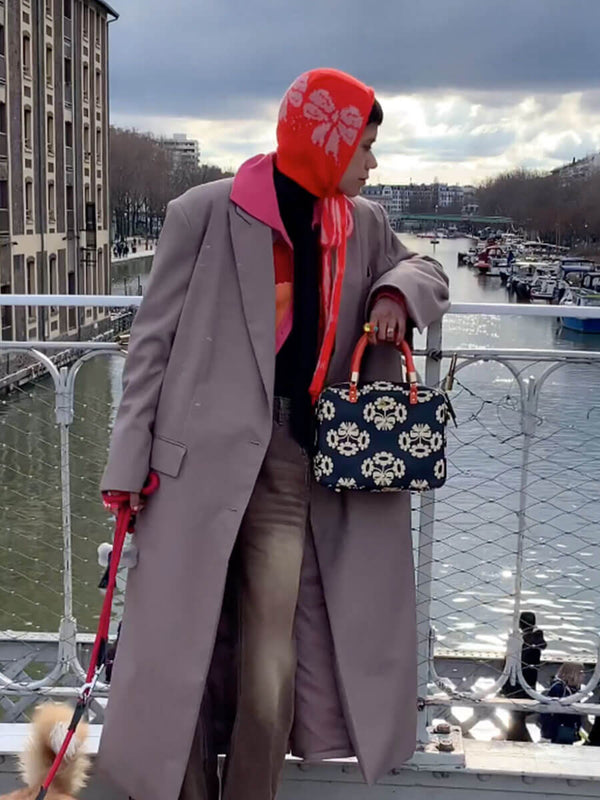 An influencer looking over the river whilst holding her Orla Kiely handbag 