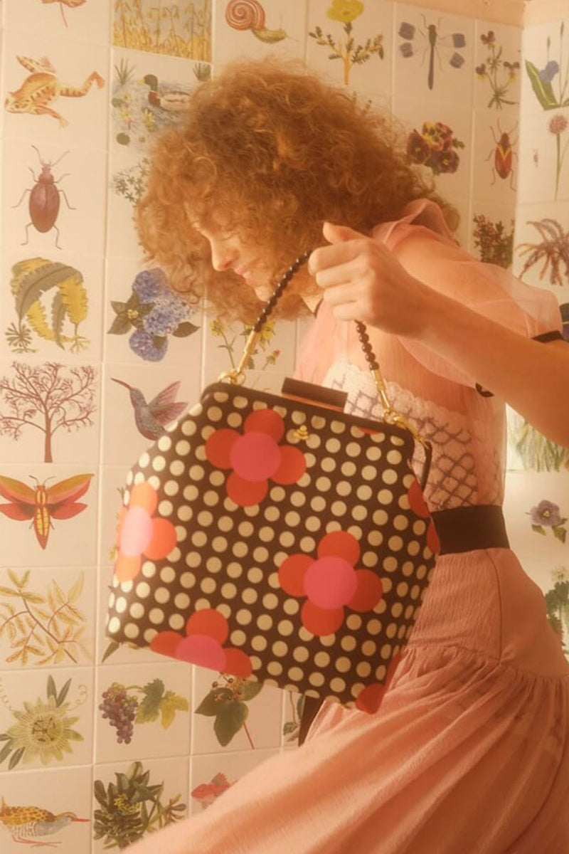 Model holding Orla Kiely Jenny D handbag in front of tiles