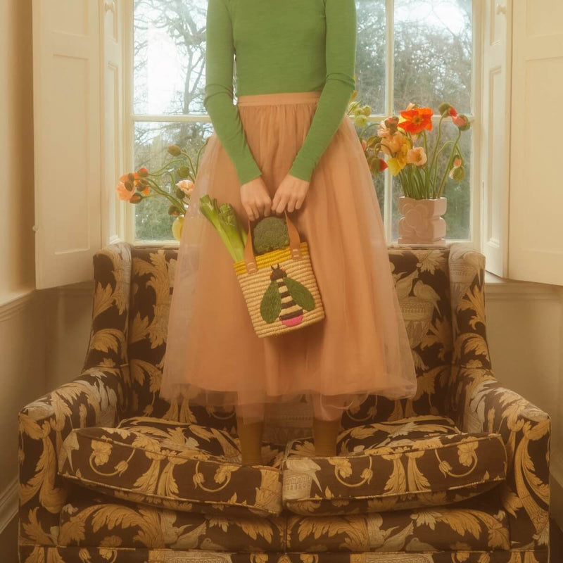 Model standing on chair with raffia Orla Kiely bag 