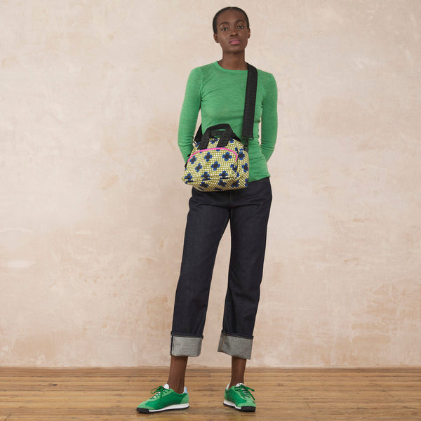 Model wearing the Radial Handbag in Flower Polka Dot Olive pattern by Orla Kiely