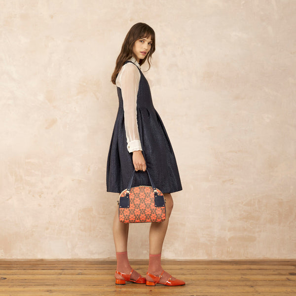 Model wearing the Luna Bowling Bag in Tomato Puzzle Flower pattern by Orla Kiely