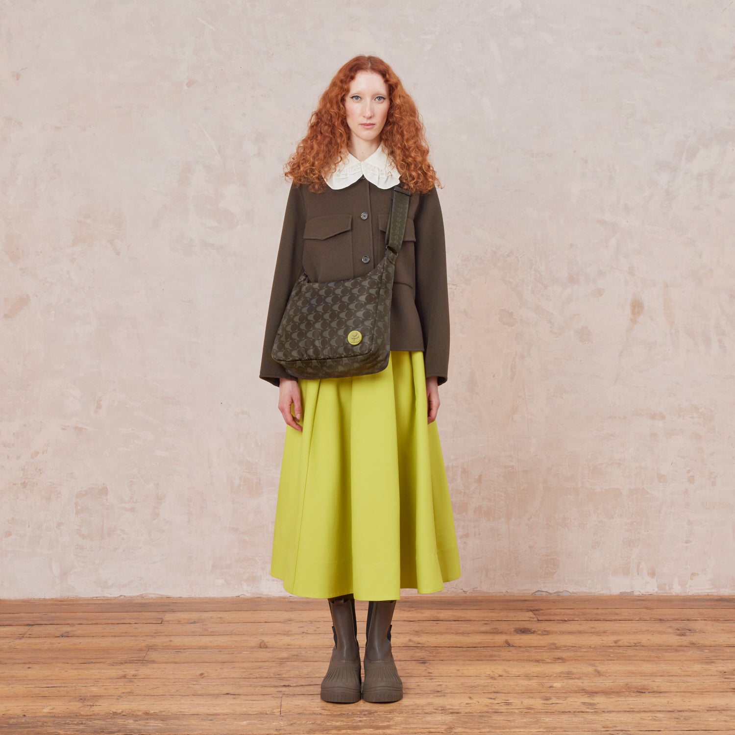 Woman wearing a crossbody bag in a black and grey pattern. The handbag features a lime stem logo detail.