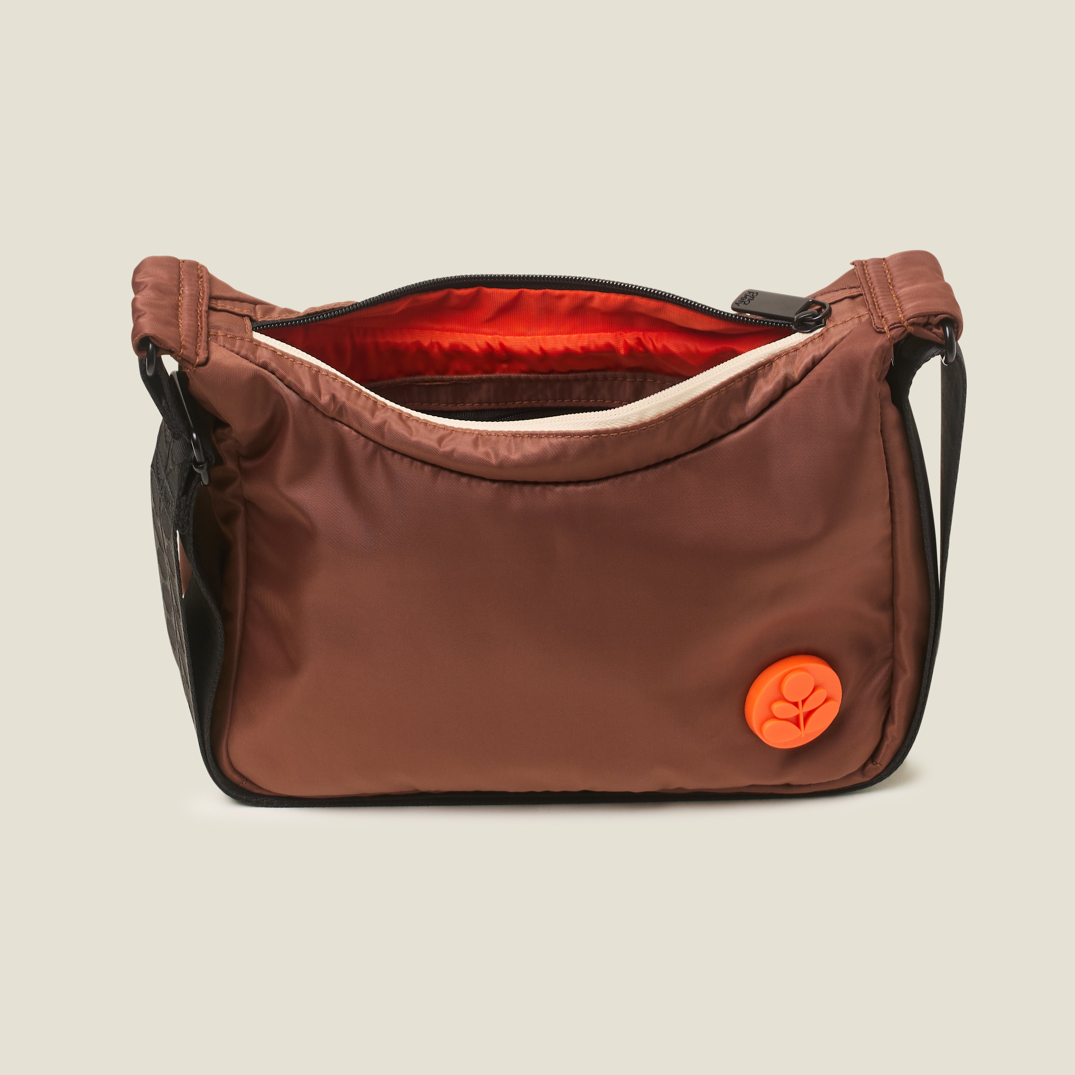 Top view of the Ratio Small bag in brown with the zipper opened to reveal orange lining, this crossbody bag features an orange Orla Kiely logo.