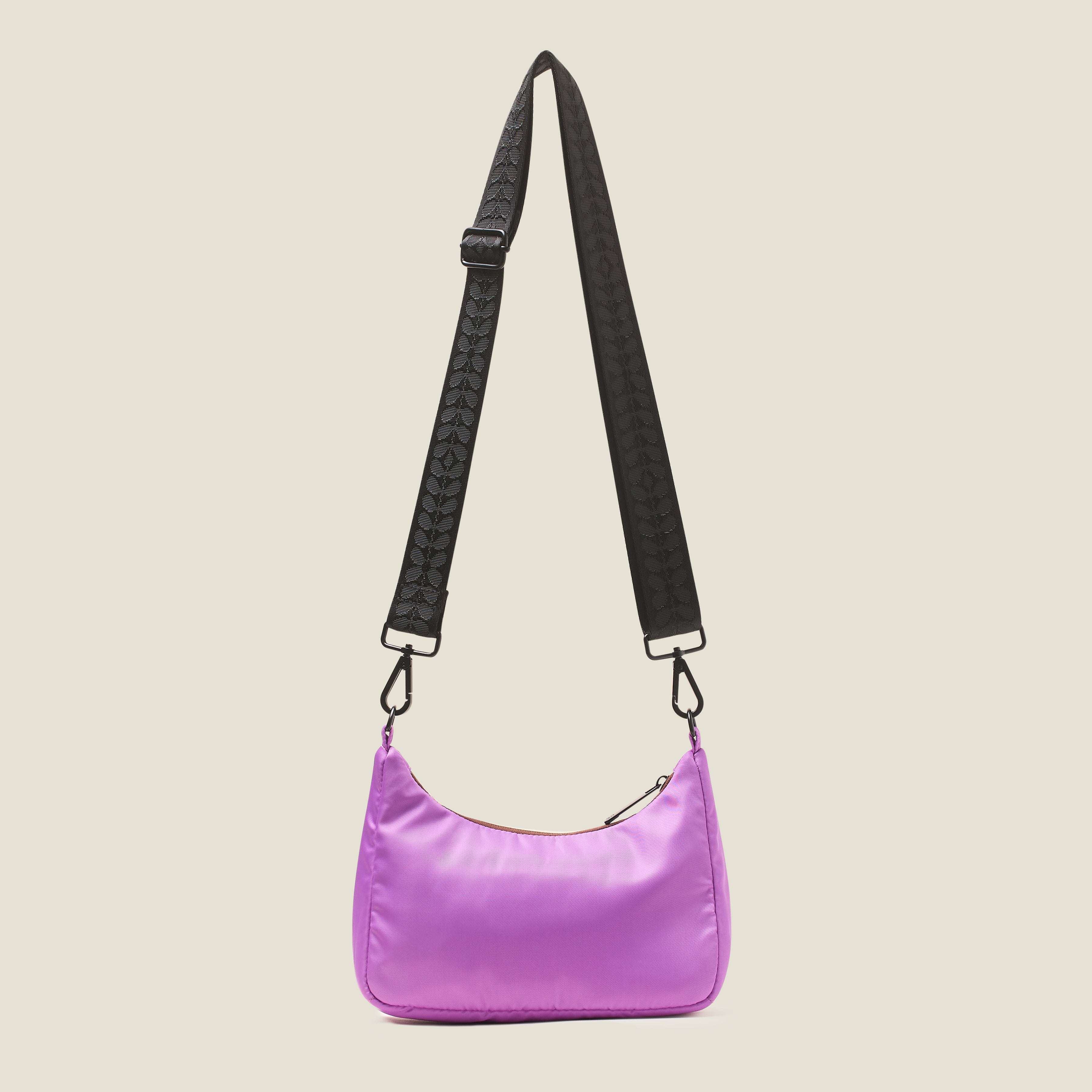 Back view of an over handbag in lilac purple with a webbing crossbody strap at full length, featuring a yellow rubber Orla Kiely stem logo  on a beige background