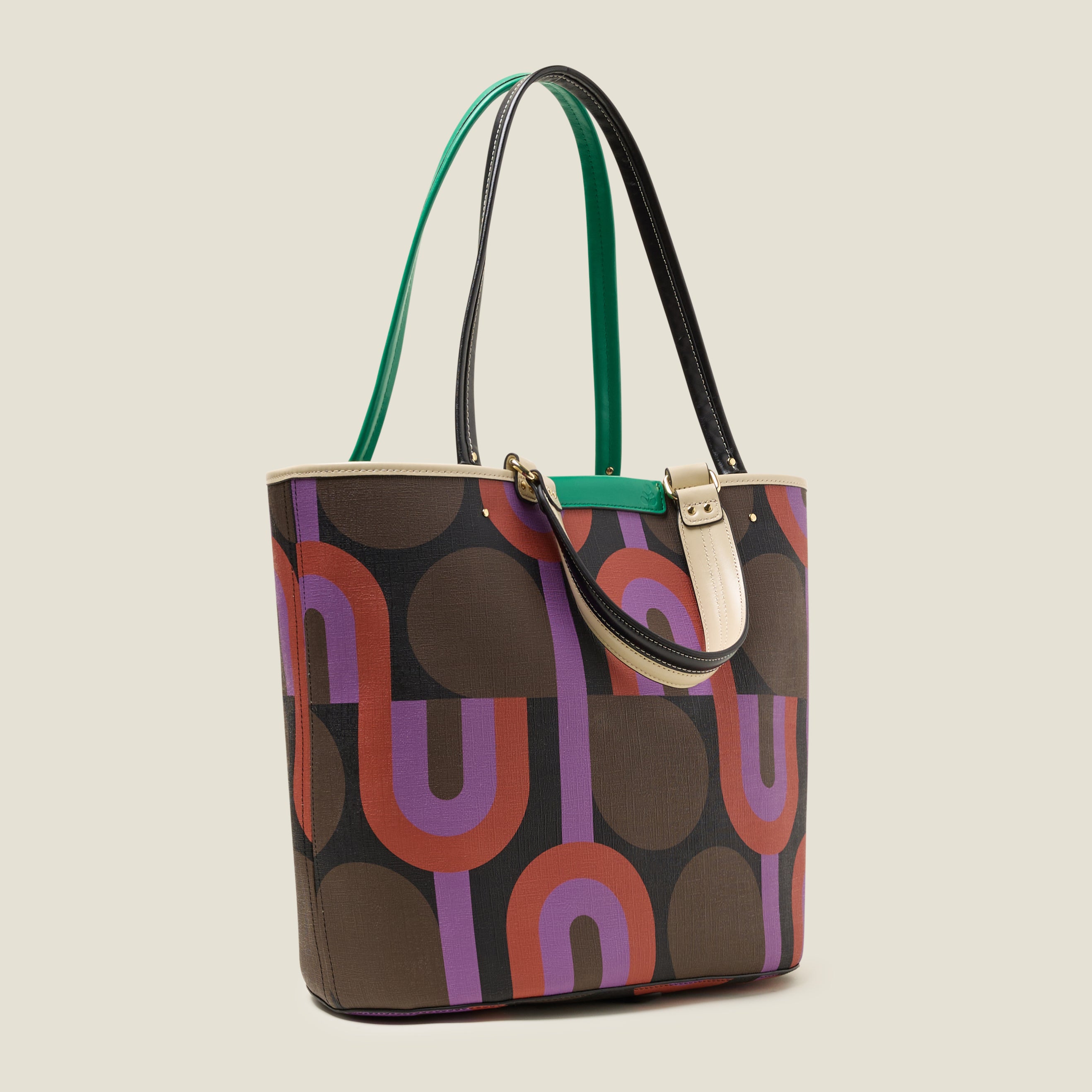 Side view of a large tote bag with purple, red, brown and black retro inspired pattern, featuring leather grab handles and shoulder straps and green branding.