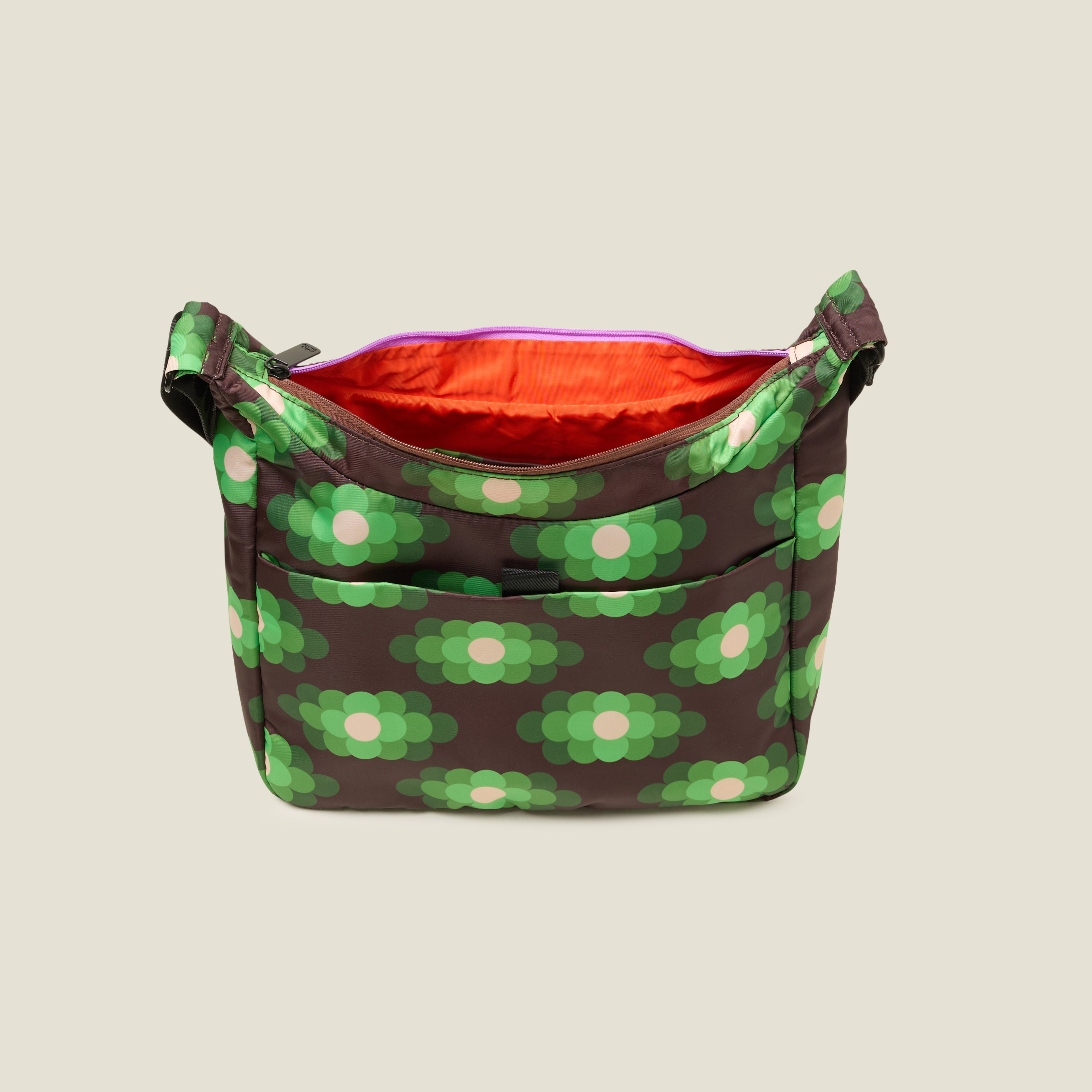 Top view of crossbody bag in a neongreen floral pattern. with zipper open to reveal the inside zip pocket and orange lining. 