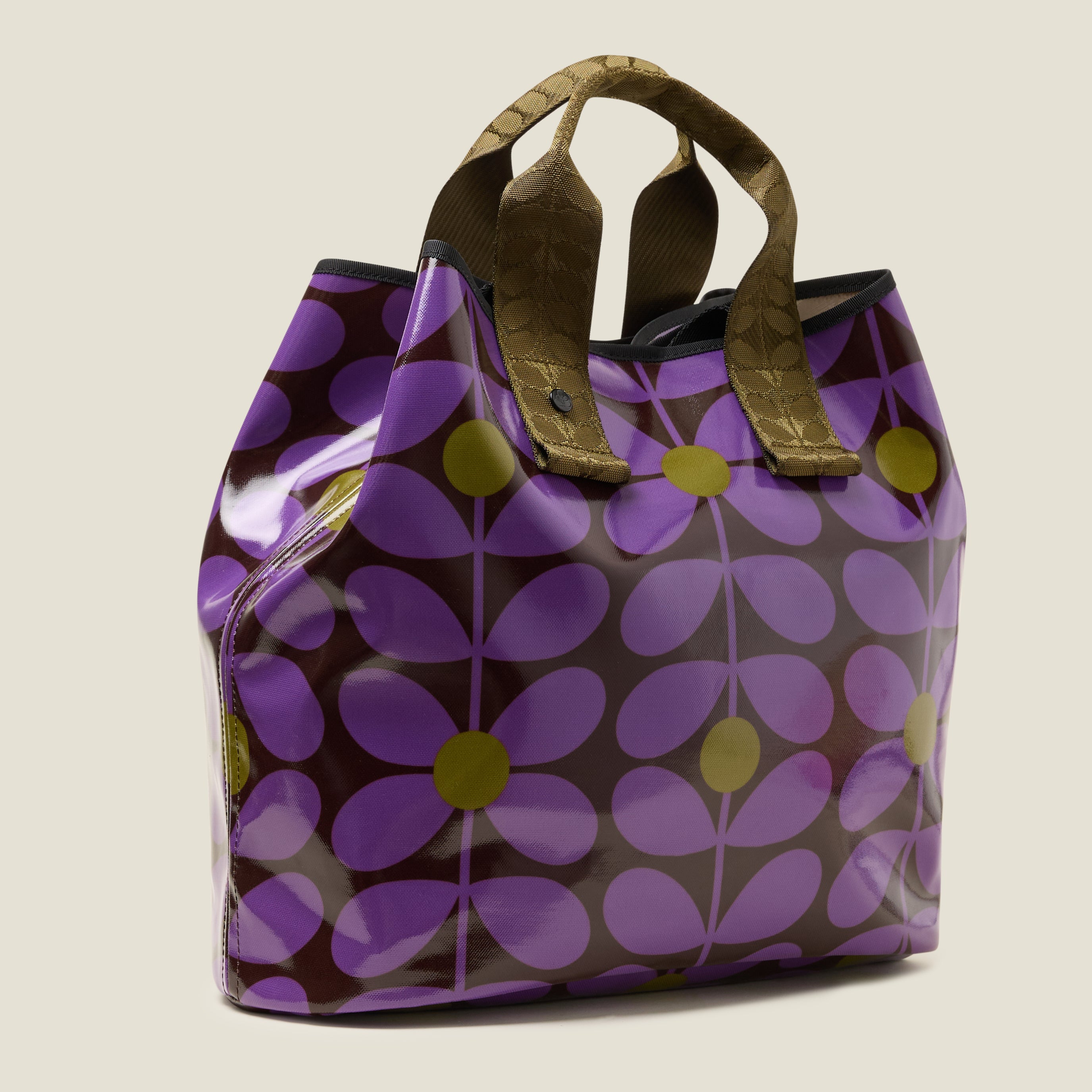 Side view of patterned tote bag with purple, brown and green floral print design, with top corners folded in for more security, with two short grab handles.