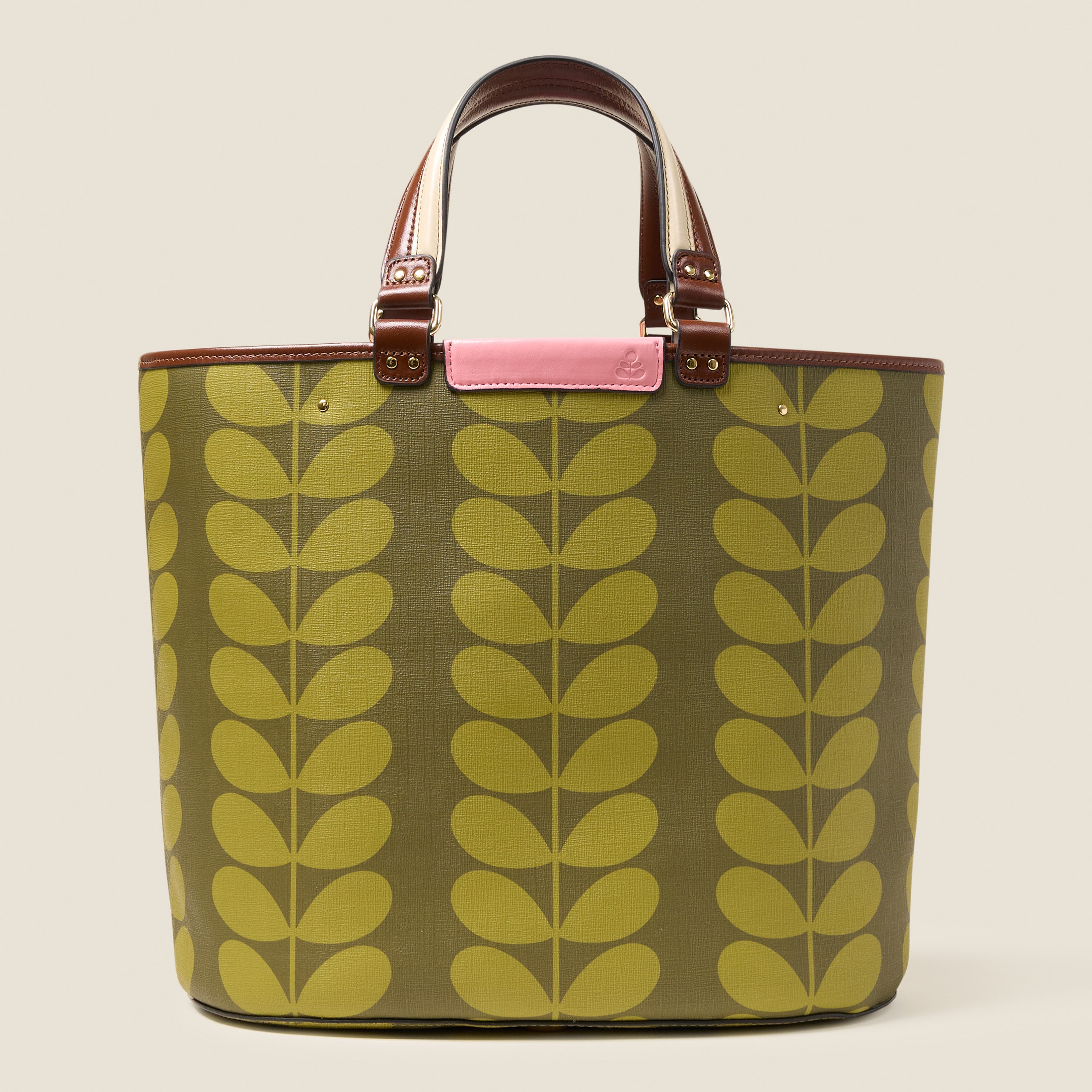 Front view of a large tote bag with green leaf pattern, featuring leather grab handles and pink branding.