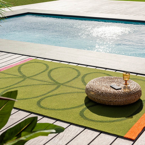 Lifestyle image of seagrass green and orange Orla Kiely outdoor rug