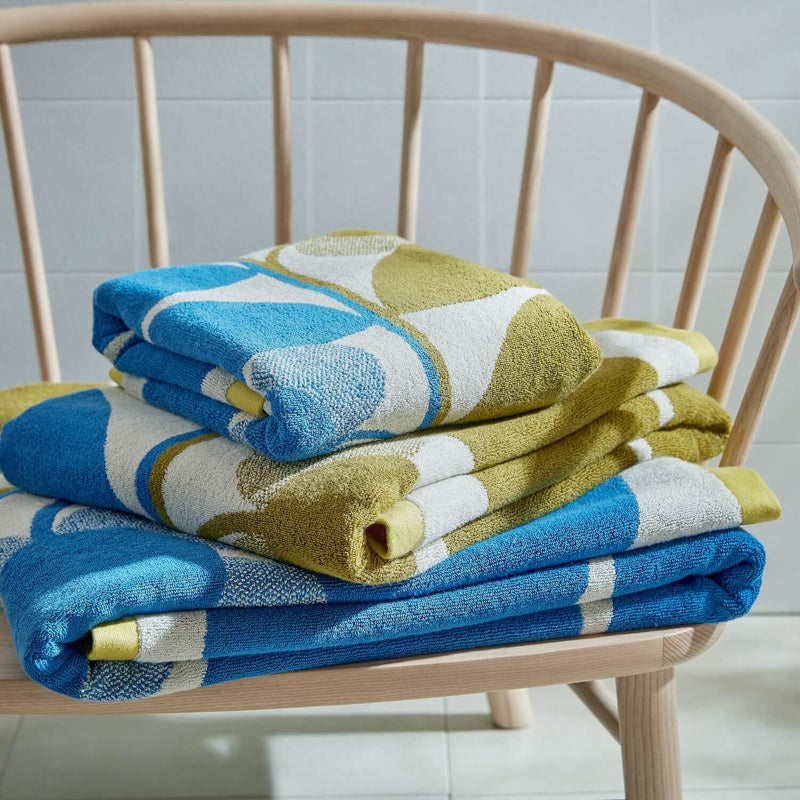 Lifestyle shot of Orla Kiely stem towels in Fawn and blue folded on chair