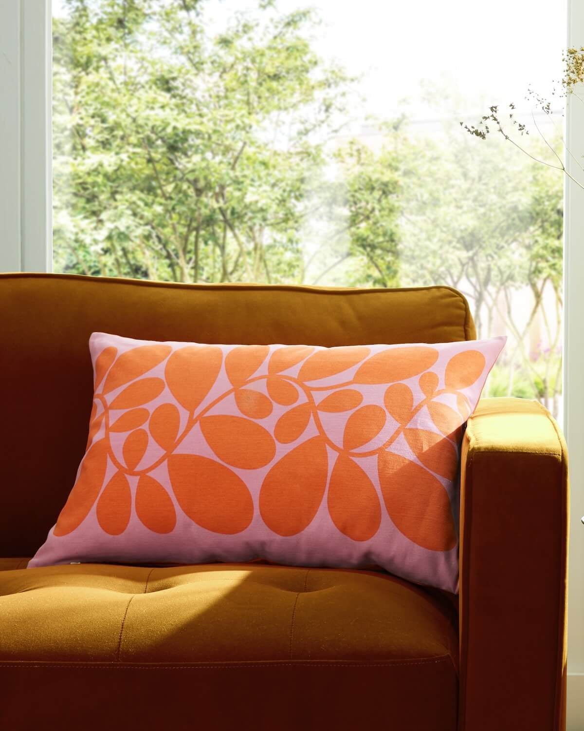 Orla Kiely sycamore stem cushion in pink on a sofa