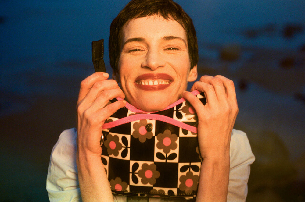 Model smiling, holding Orla Kiely Flower Pot Chestnut bag