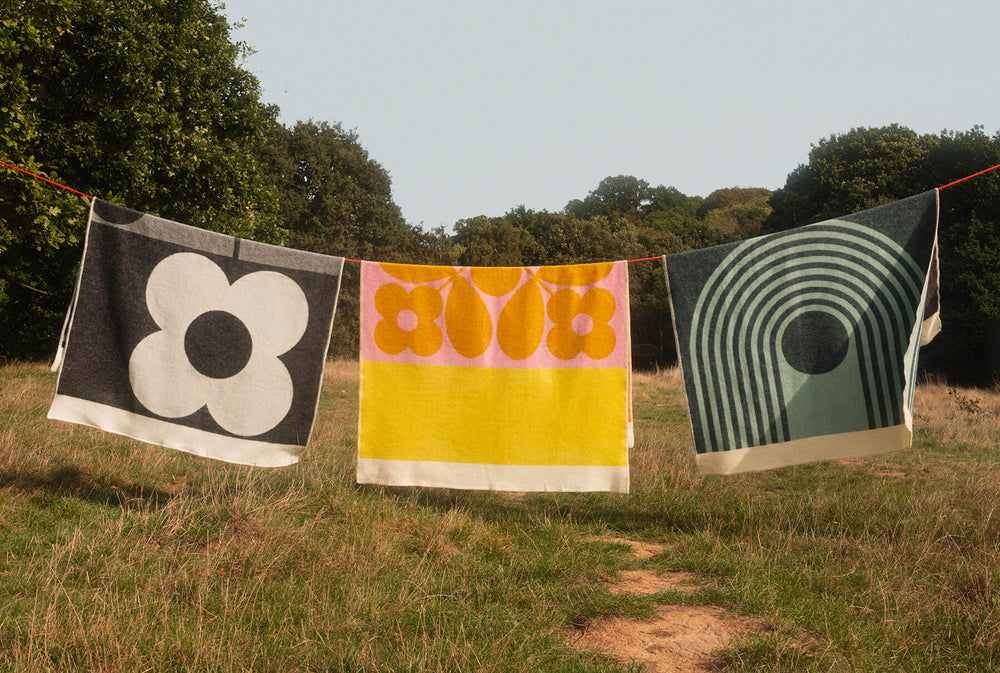 Orla Kiely blankets on a clothes line with a blue sky and trees behind it